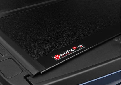 The BAKFlip Fibermax badge being displayed on the corner of a textured black panel.